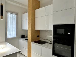 a kitchen with white cabinets and a black microwave at Maison Chanel in Milan +3 photos