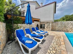 a row of blue and white lounge chairs next to a swimming pool at Apartman Milly in Grižane