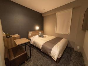 een kleine slaapkamer met een bed en een raam bij Super Hotel Premier Sendai Kokubuncho Tennenonsen in Sendai