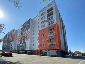 an apartment building in a parking lot at Уютная студия в ЖК Шахар возле ТРЦ Asia Park! in Almaty