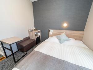 um pequeno quarto com uma cama e uma cadeira em Super Hotel Premier Sendai Kokubuncho Tennenonsen em Sendai