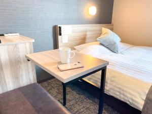 a small table with a cup on it next to a bed at Super Hotel Premier Sendai Kokubuncho Tennenonsen in Sendai