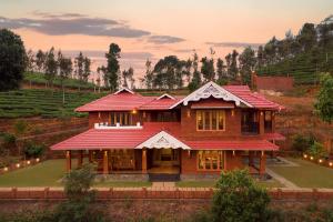 a house with a red roof on a hill at Regal Retreat by VEO - Part of StayVista in Wayanad