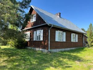 an old wooden house with a gambrel roof at Domek Radość in Cieksyn