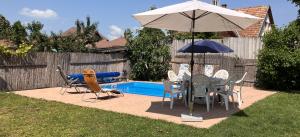 a table and chairs with an umbrella next to a pool at Lellei Pihenőház Balatonlelle in Balatonlelle