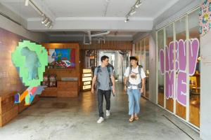 dos hombres caminando por un pasillo en una tienda en OwlStay Flip Flop Hostel - Garden en Taipéi
