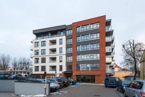 een hoog gebouw met auto's geparkeerd op een parkeerplaats bij #MazuryGlamour in Giżycko