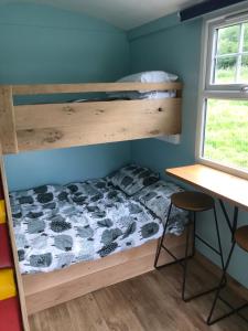 a bunk bed in a room with a desk at Shepherds Hut (Benny's) in Cullompton
