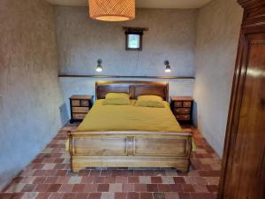 een slaapkamer met een bed met gele lakens en 2 nachtkastjes bij Gîte tout confort dans le Perche in Margon