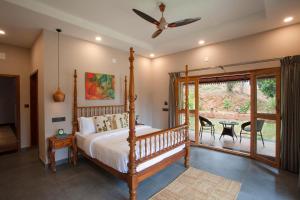 a bedroom with a bed and a patio with a table at Regal Retreat by VEO - Part of StayVista in Wayanad +29 photos