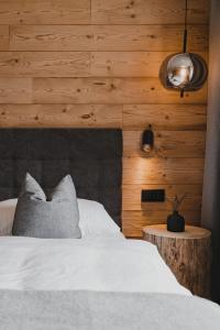 1 dormitorio con 1 cama y pared de madera en Stoacherhof Apartments, en Matrei am Brenner