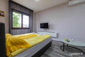 a bedroom with a large yellow bed and a table at Apartmani Nina S in Bajina Bašta