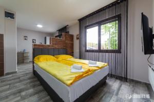 a bedroom with a bed with yellow sheets and a window at Apartmani Nina S in Bajina Bašta