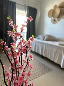a vase with pink flowers in a room with a bed at VG FUN 308 Praia do Futuro in Fortaleza