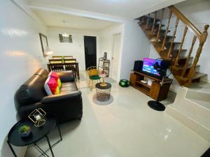 a living room with a couch and a tv and stairs at Gillera Staycation in Lipa in Lipa