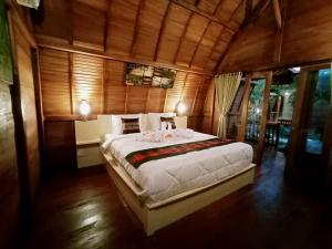 1 dormitorio con 1 cama grande en una habitación de madera en Maha Nusa Menjangan en Banyuwedang
