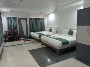 una habitación de hotel con 2 camas y una silla en HOTEL BLUE MOON, en Nellore