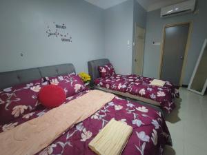 a bedroom with two beds with purple sheets and flowers at Homestay Kasyaf HUKM Cheras With Wi-fi in Kuala Lumpur