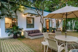 a patio with a couch and an umbrella and a table and chairs at Tranquilisle in Kandy