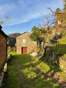 un edificio de ladrillo con una puerta roja en un patio en Casa do Moura, en Arcos de Valdevez