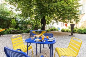 un tavolo blu con sedie gialle e cibo sopra di L'Abeille - Boutique Apartments a Nizza