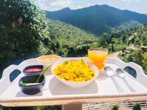 a table with bowls of food and a glass of orange juice at Aranya Mukteshwar in Mukteswar