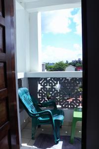 une chaise verte assise sur un balcon avec fenêtre dans l'établissement Bamburi 2BR Apartment, à Mombasa