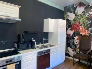 a kitchen with white cabinets and a flower wallpaper at Kaptainshuus Apartment A in Leer