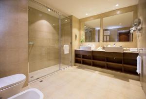 a bathroom with a shower and two sinks and a toilet at Copthorne Downtown by Millennium in Abu Dhabi
