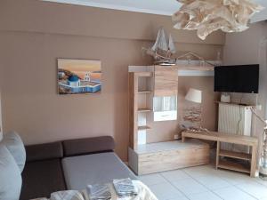 a living room with a couch and a tv at Ester's Sea Side apartment in Neoi Epivates
