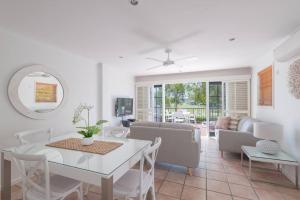Villa Aqua 6 - Riverfront Noosaville في نوسافيل: غرفة معيشة مع طاولة وكراسي بيضاء