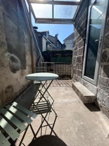 a table and a chair on a patio with a window at Blum in Brive-la-Gaillarde