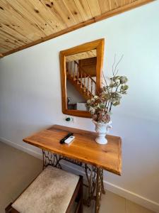 a table with a mirror and a vase with flowers on it at Nashos Bungalows in (( Spile ))