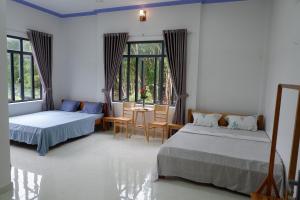 a bedroom with two beds and a table and chairs at Hương Tràm in Hồ Ðá