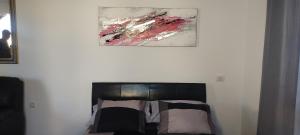 a bedroom with a bed with a painting on the wall at Appartamento Lusi Sole e Mar in Costa Del Silencio