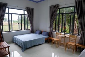 a bedroom with a bed and a table and windows at Hương Tràm in Hồ Ðá