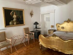 1 dormitorio con 1 cama, una pintura y sillas en D.R.Rome Spanish Luxury Suites en Roma