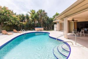 uma piscina com cadeiras e uma casa em Casa Del Sol-Huge 3br! Beaches Pool and Hot Tub! em Lake Worth