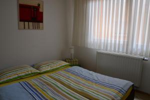 a bedroom with a bed with a striped blanket and a window at Apartment Adagio in Zagreb