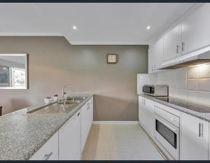 a white kitchen with a sink and a counter at Golf Views Apartment in Mulwala