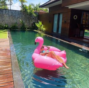 a woman riding on a pink flamingo in a pool at Eko Villa Seminyak in Seminyak