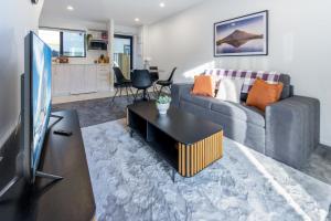 sala de estar con sofá y TV en A Road Away from Hagley Park 2 bed 2 bath, en Christchurch