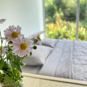 a vase with purple flowers in front of a couch at Royal mountain view (วิวเขาหลวง) in Ratchaburi