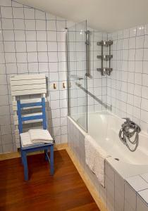 een badkamer met een blauwe stoel en een bad bij Maison d'Hôtes - L'Hôthentique in Gaillan-en-Médoc