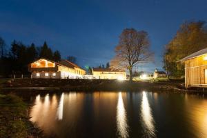 Aussicht auf ein Haus und einen See in der Nacht in der Unterkunft GutsAlm Harlachberg in Bodenmais