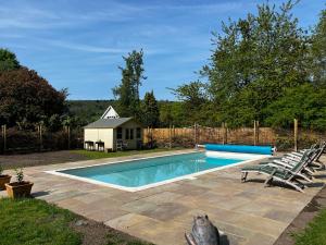 a swimming pool with two chairs and a house at The Honeypot at Newlands in Bury in Bury