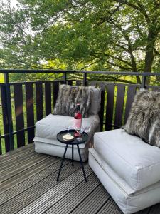 two chairs and a table with a glass of wine on a deck at Ferienhaus am Wald in Frankenau