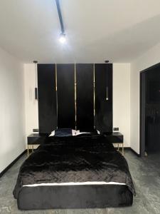 a bedroom with a large black bed with two tables at "Apollo" - domek, apartamenty i pokoje z klimatyzacją in Krynica Morska