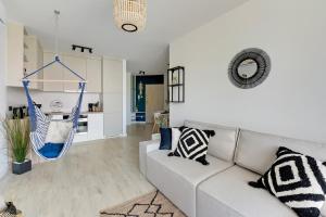 a living room with a couch and a hammock at Flatbook Apartamenty - Sztutowo Baltic Garden in Sztutowo