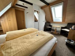 a bedroom with two beds and a chair and a window at Hotel Peters Schwalbennest in Neuharlingersiel